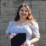 Smiling woman, holding a decorated diploma container.