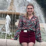 Smiling woman sitting in front of a fountain.