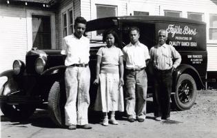 4 people stand in front of a car.