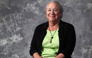 A woman wearing a green shirt and black sweater.