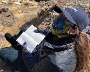 Woman wearing a mask, reading a book.