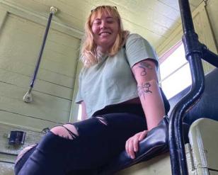 Woman smiling, sitting in a booth.  the camera angle is from below.