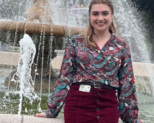 Smiling woman sitting in front of a fountain.