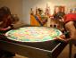 3 men slowly adding sand to the mandala