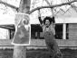 Woman in overalls swinging from a tree.