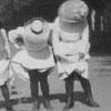 2 women showing their stockings while wearing early 20th century bathing suits.